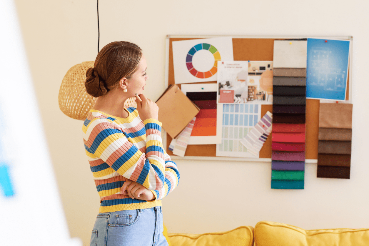 A woman contemplates color samples on a mood board in a bright room.