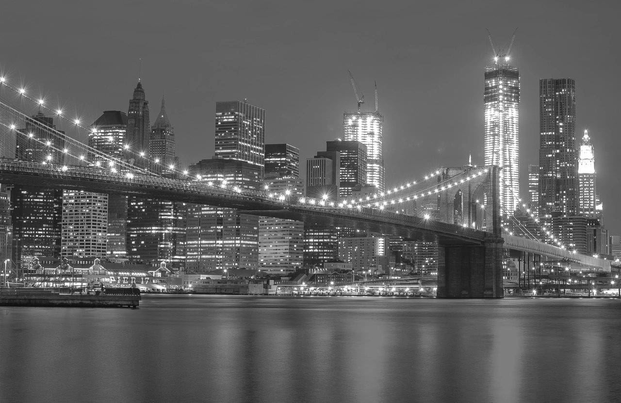 New york city skyline at night with brooklyn bridge in black and white.