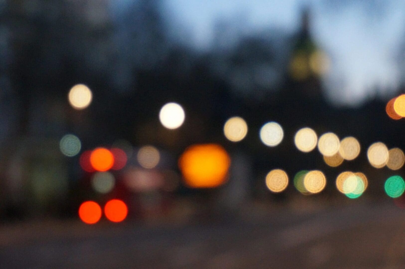 A blurred image of city lights at dusk or night.