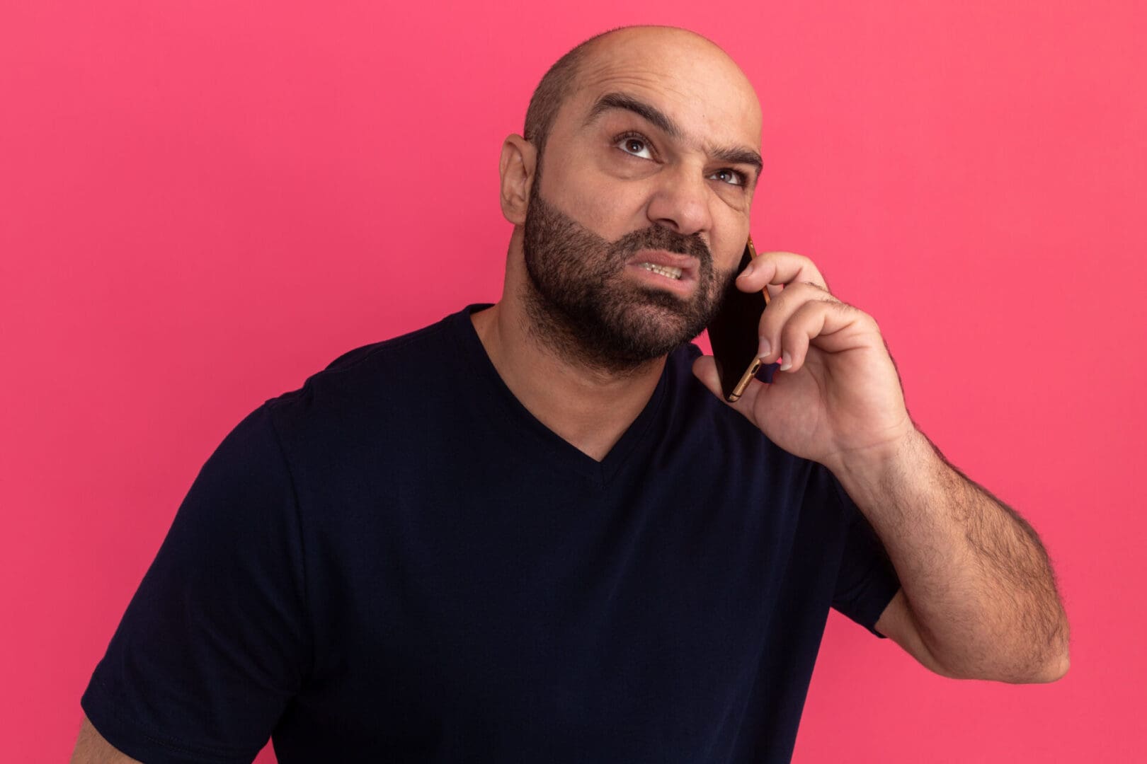 Man with a skeptical expression talking about trigger leads on the phone against a pink background.
