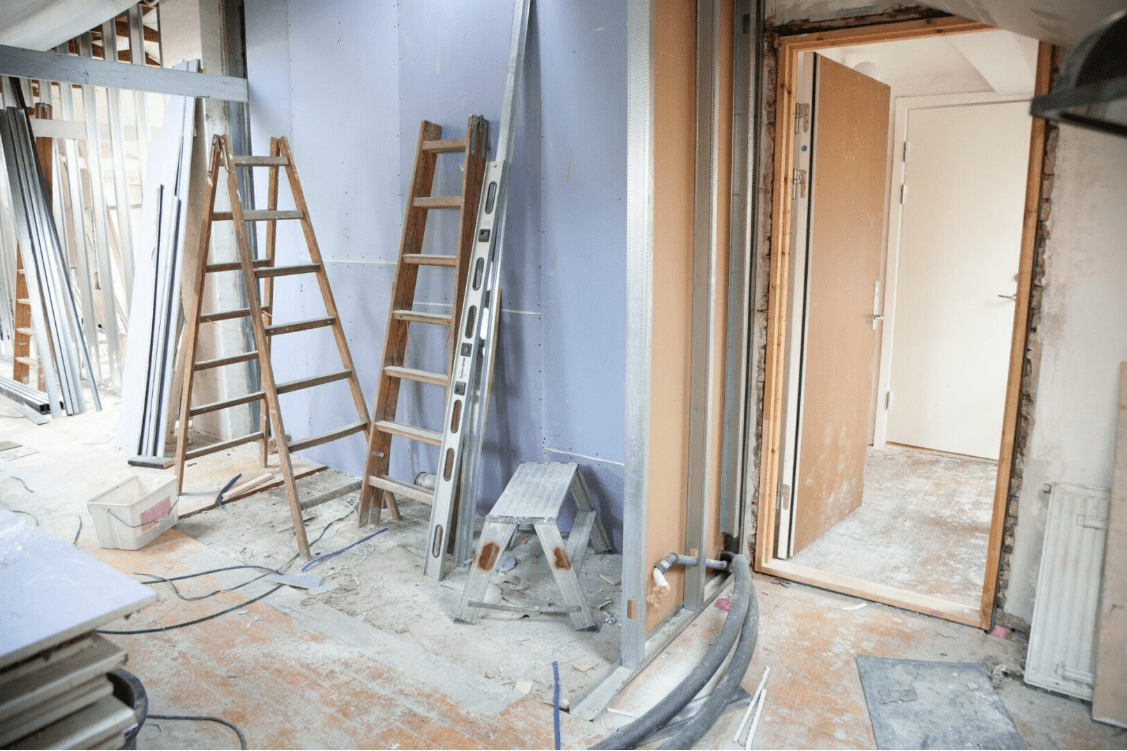 Interior space undergoing home renovation with ladders and construction materials.