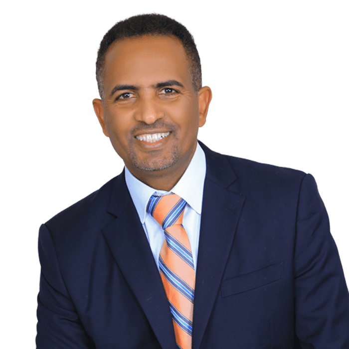 A smiling man wearing a preferred suit and striped tie.