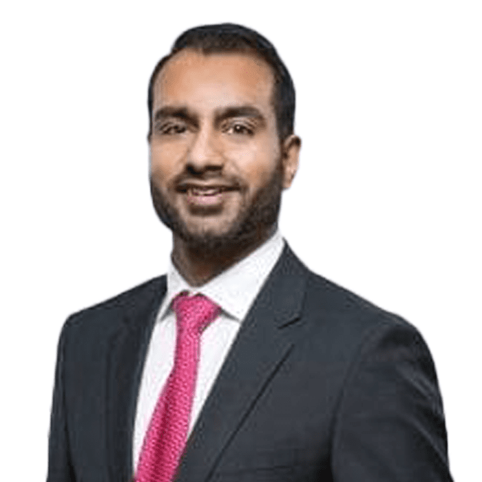 A preferred professional man in a suit with a pink tie smiling at the camera.