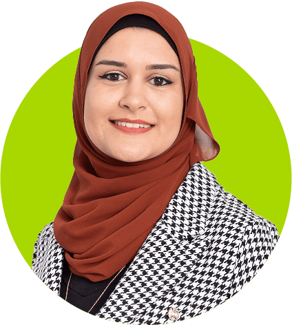 A woman wearing a hijab and a preferred houndstooth jacket smiles at the camera against a green background.