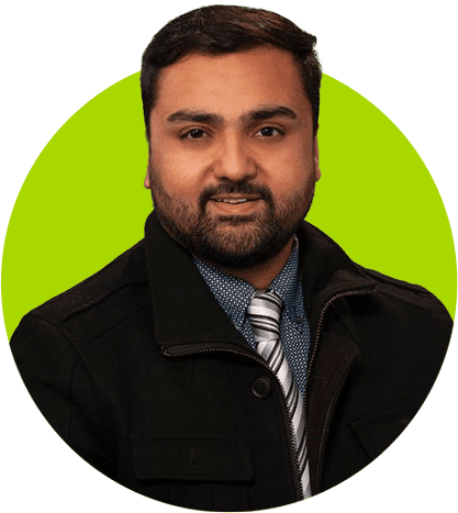 A man in a preferred black coat and striped tie with a slight smile against a green background.