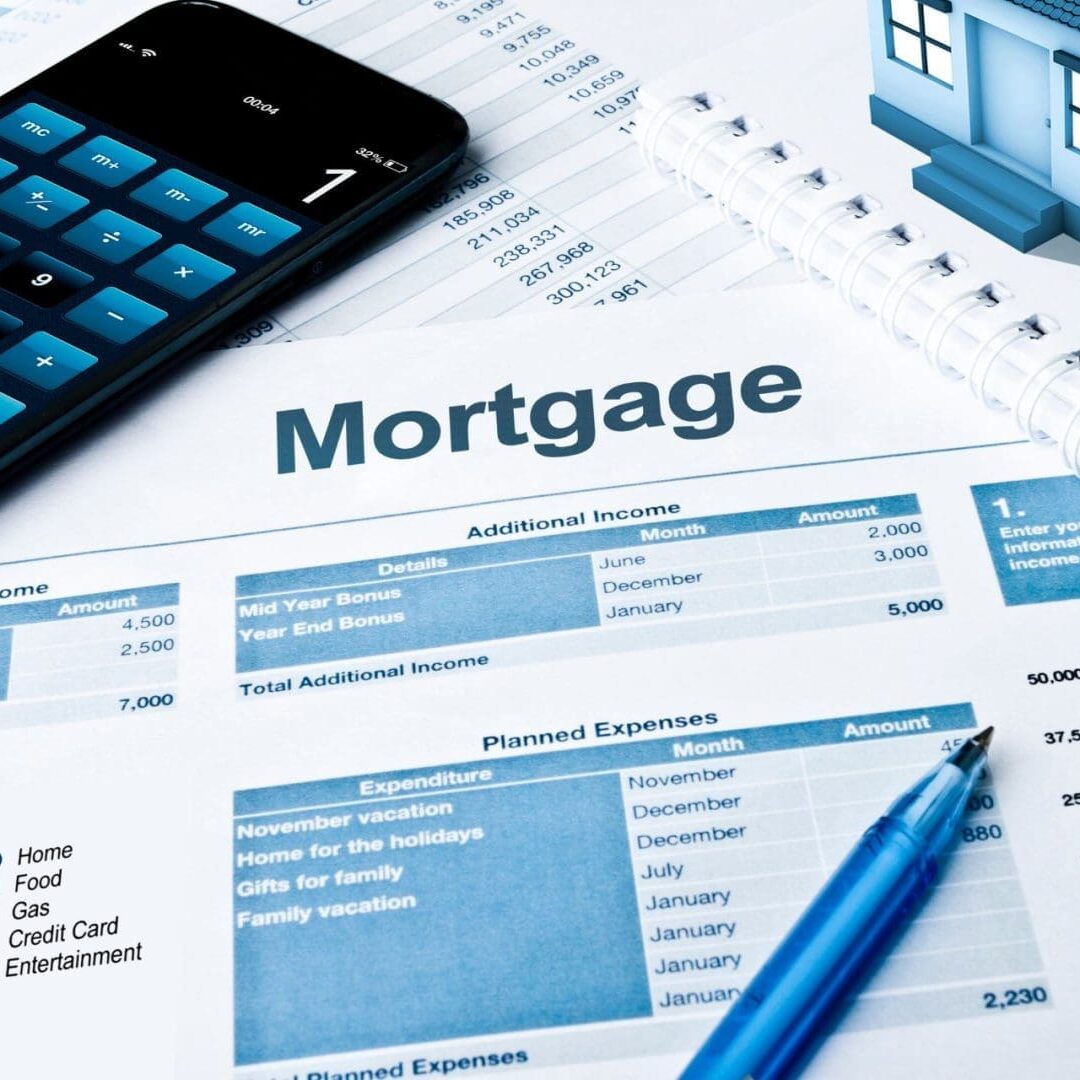 Mortgage application paperwork with financial documents, a calculator, and house model on a desk.