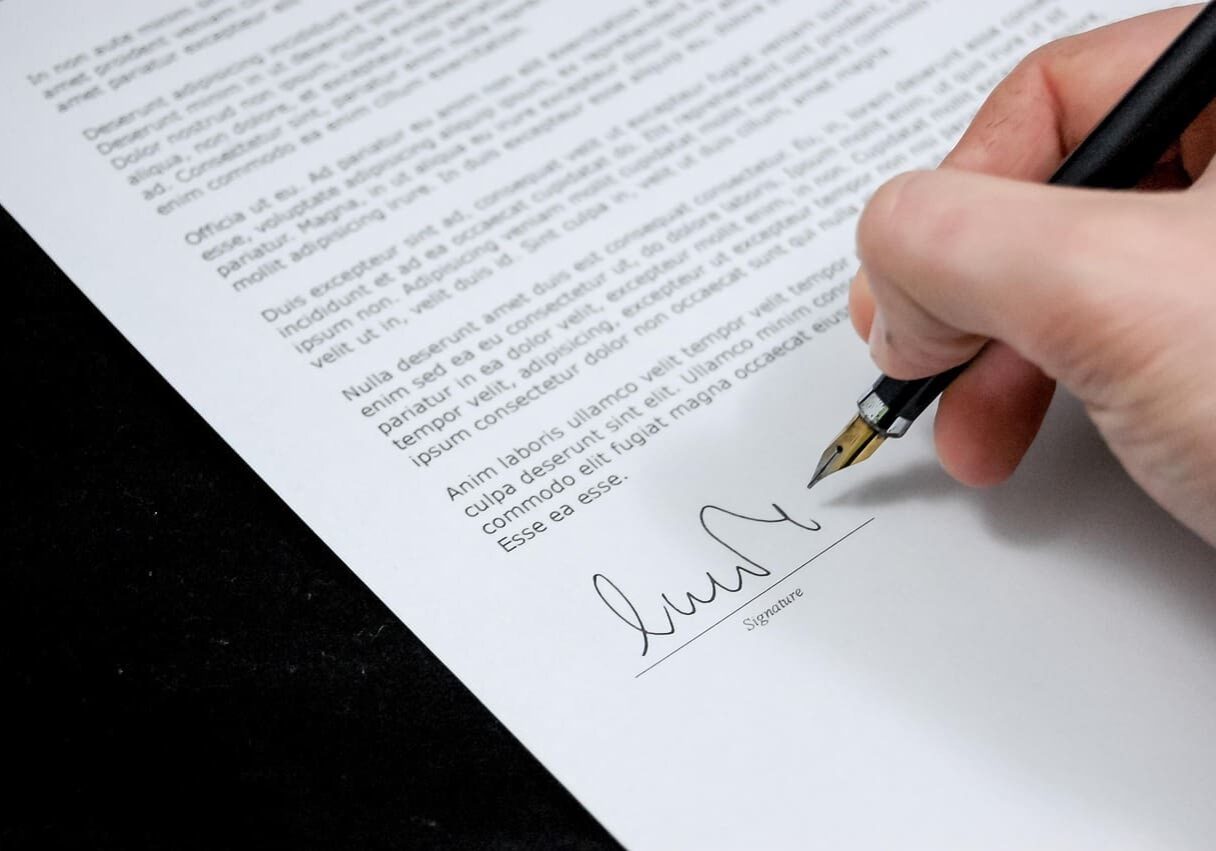 Hand signing a document with pen.