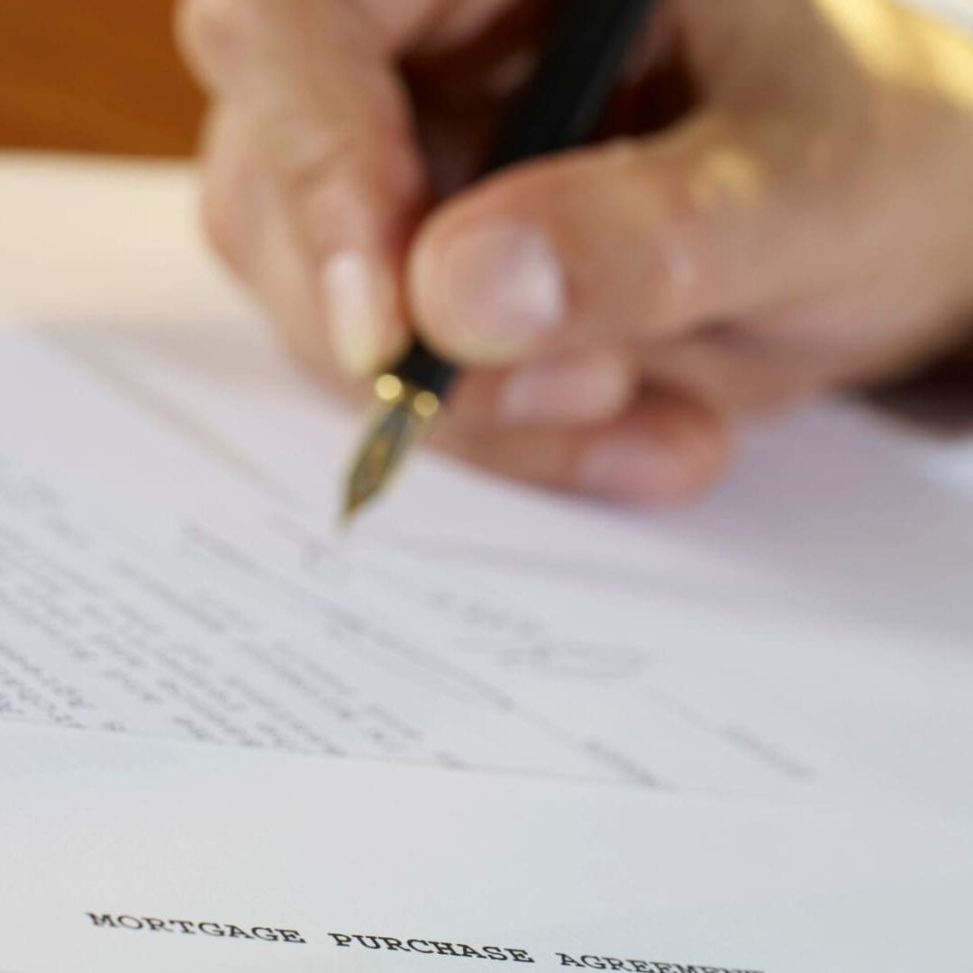 A person signing documents for a mortgage purchase agreement.