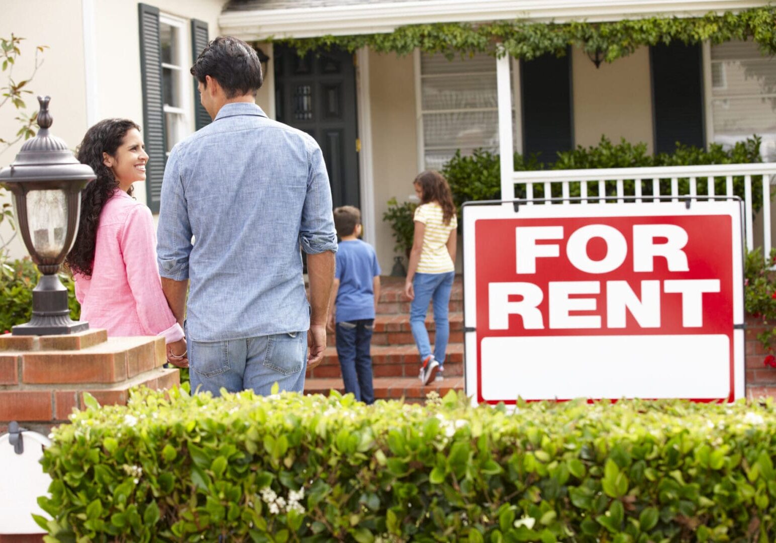 Family looking at a house with a "for rent" sign in the front yard, interested in residential programs in the US.