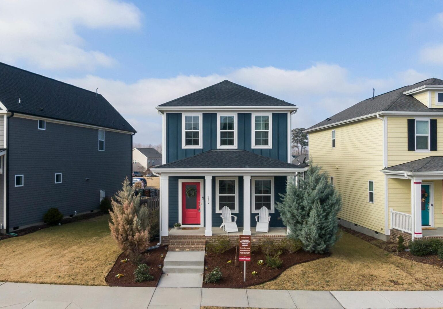 Three suburban houses with front yards.
