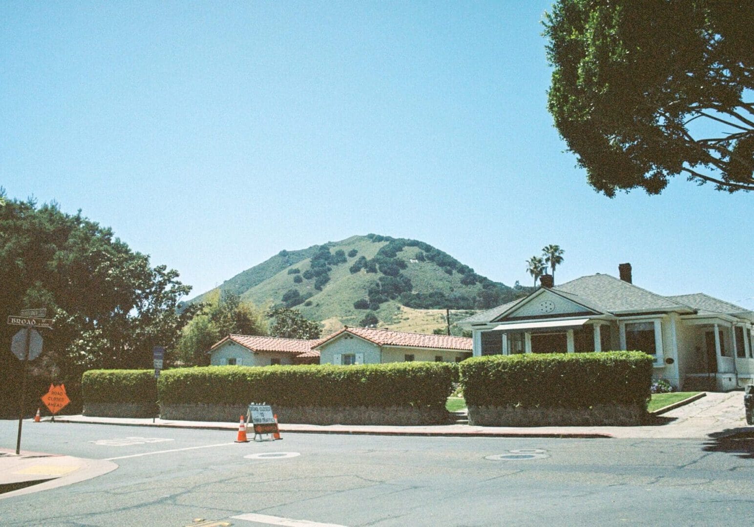 Suburban street with houses and green hill.